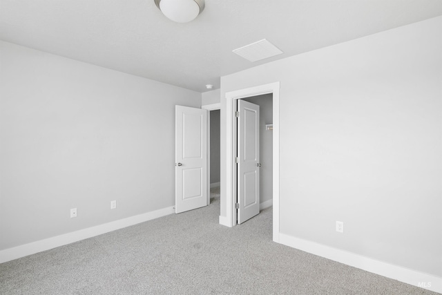 unfurnished bedroom with light carpet, a spacious closet, and baseboards