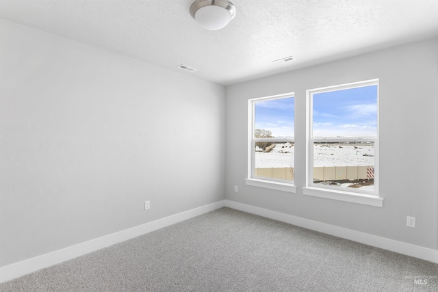 unfurnished room featuring carpet floors, visible vents, a textured ceiling, and baseboards