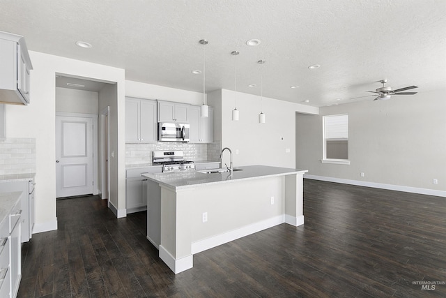 kitchen with tasteful backsplash, dark wood finished floors, an island with sink, appliances with stainless steel finishes, and a sink