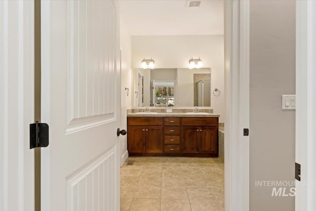 bathroom with double vanity, visible vents, a shower stall, and a sink