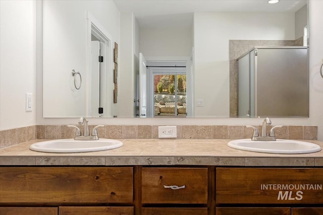 full bath featuring double vanity, a shower stall, and a sink