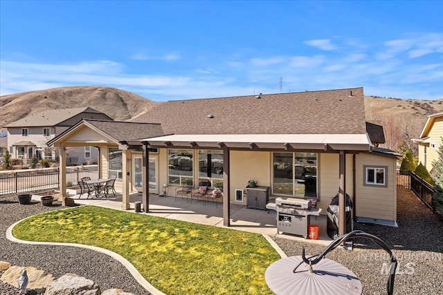 rear view of house with a patio, a yard, fence, and roof with shingles