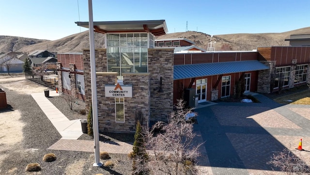 view of front of house featuring a mountain view, stone siding, and metal roof