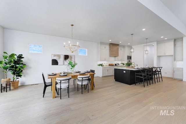 dining room with light hardwood / wood-style flooring and a chandelier