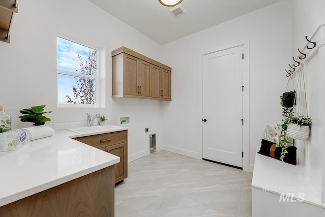 clothes washing area featuring electric dryer hookup, hookup for a washing machine, sink, and cabinets