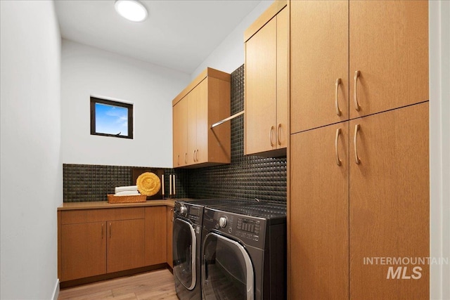 laundry area with cabinet space, washing machine and dryer, and light wood finished floors