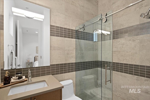 bathroom featuring a stall shower, tile walls, toilet, vanity, and tasteful backsplash