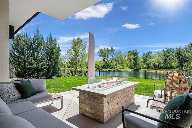 view of patio with a water view, an outdoor living space with a fire pit, and view of scattered trees