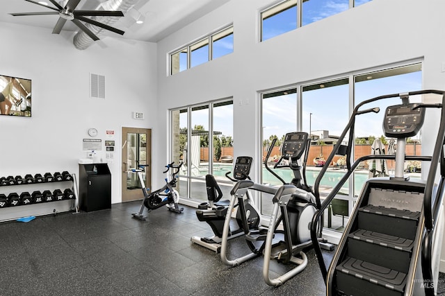gym featuring a ceiling fan and a high ceiling