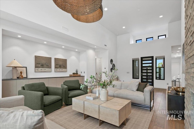 living room featuring hardwood / wood-style floors, a towering ceiling, and recessed lighting