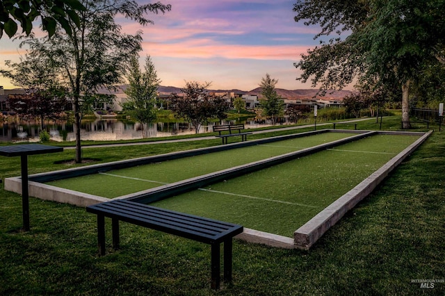 surrounding community featuring a bocce ball area, a water view, and a yard