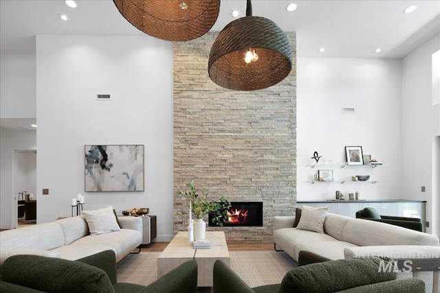 living room featuring a towering ceiling, a fireplace, recessed lighting, and wood finished floors
