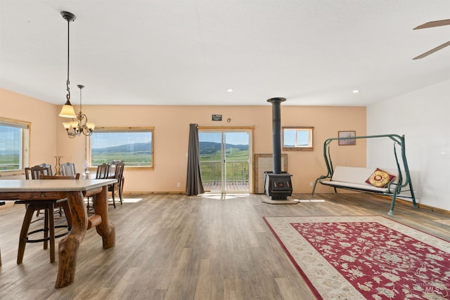 interior space featuring ceiling fan with notable chandelier, a wood stove, and wood-type flooring