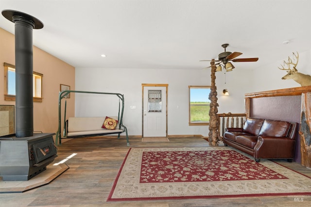 interior space featuring ceiling fan, a wood stove, and hardwood / wood-style floors