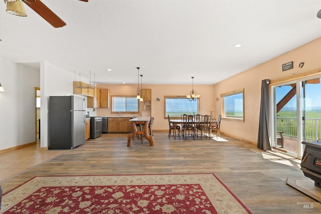 kitchen featuring stainless steel fridge, wood-type flooring, range, and ceiling fan with notable chandelier