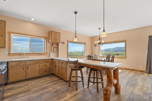 kitchen with dark hardwood / wood-style floors, kitchen peninsula, a notable chandelier, sink, and pendant lighting