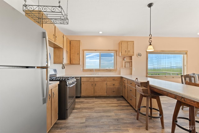 kitchen with gas range oven, white fridge, dark hardwood / wood-style floors, sink, and pendant lighting