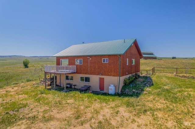 back of property featuring a deck, a yard, and a rural view