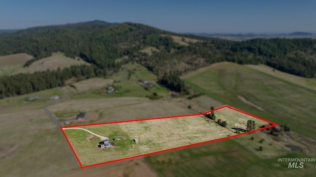 aerial view of sparsely populated area with a heavily wooded area, a mountainous background, and property boundaries highlighted