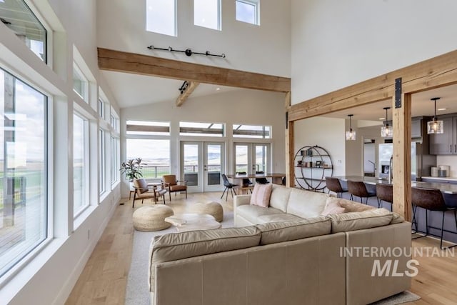 living area featuring high vaulted ceiling, healthy amount of natural light, light wood-type flooring, and beamed ceiling