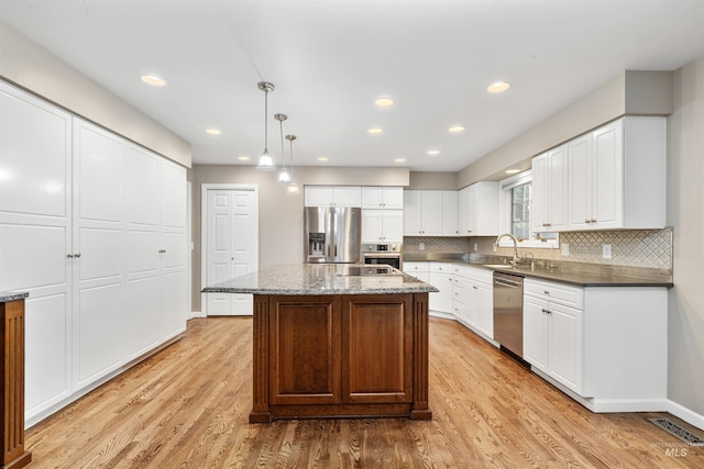 2220 14th St, Lewiston, ID 83501 - kitchen featuring appliances with stainless steel finishes, light wood-style flooring, decorative backsplash, a sink, and hanging light fixtures