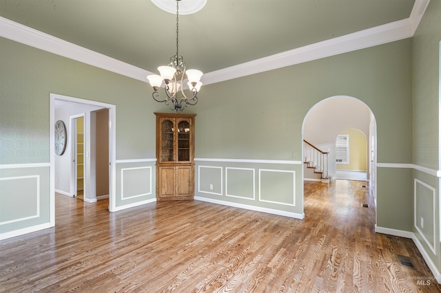 2220 14th St, Lewiston, ID 83501 - spare room featuring arched walkways, ornamental molding, wainscoting, a chandelier, and wood finished floors