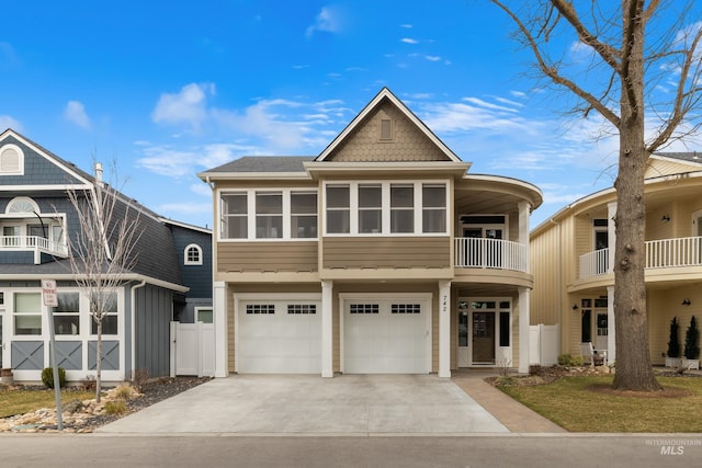 view of front facade featuring driveway, a garage, a balcony, roof with shingles, and fence