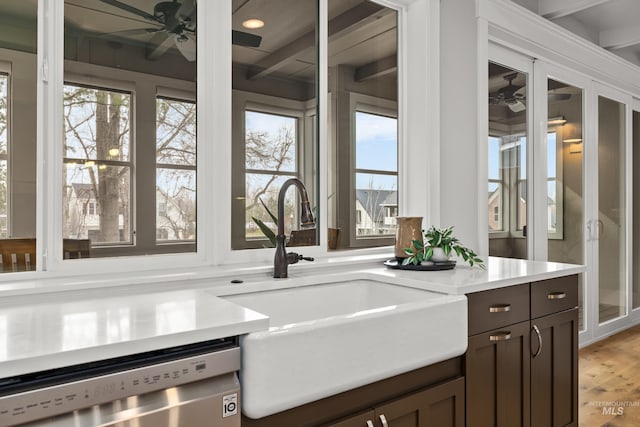 kitchen with light countertops, stainless steel dishwasher, a sink, ceiling fan, and dark brown cabinets