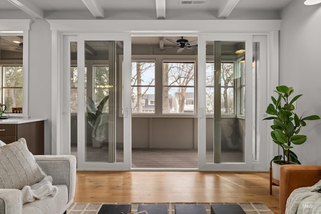 doorway to outside featuring a ceiling fan, visible vents, wood finished floors, and beamed ceiling