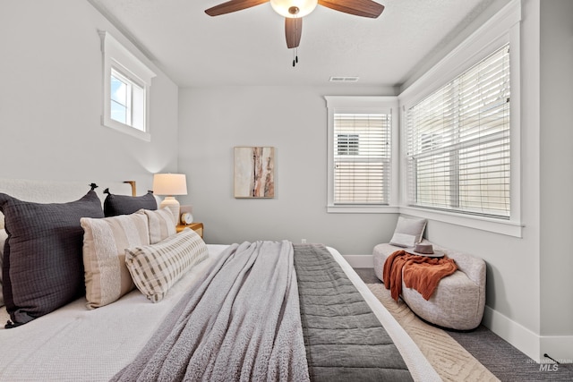 carpeted bedroom featuring baseboards, visible vents, and a ceiling fan