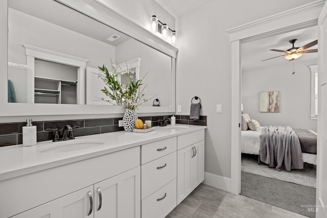 ensuite bathroom with connected bathroom, double vanity, a sink, and a ceiling fan