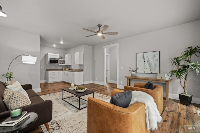 living room with light wood-style floors, ceiling fan, and baseboards