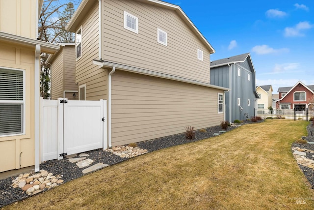 view of side of property with a lawn, fence, and a gate