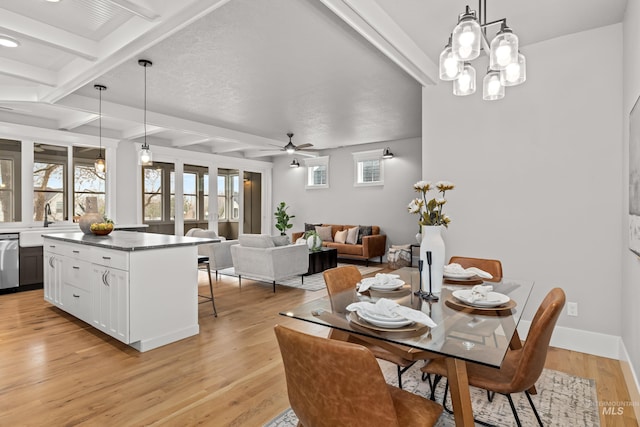 dining area with ceiling fan with notable chandelier, coffered ceiling, baseboards, light wood-style floors, and beamed ceiling