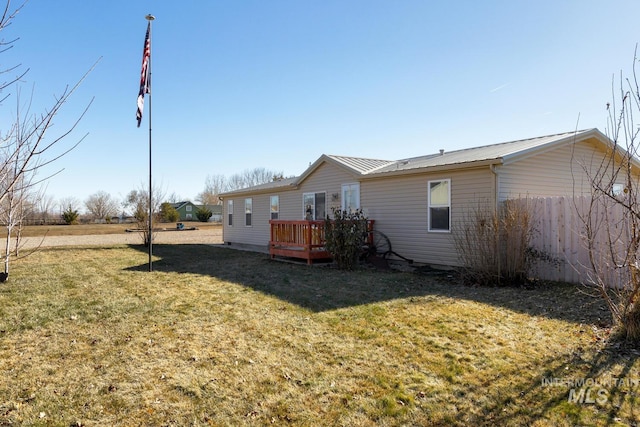 rear view of property with a wooden deck and a lawn