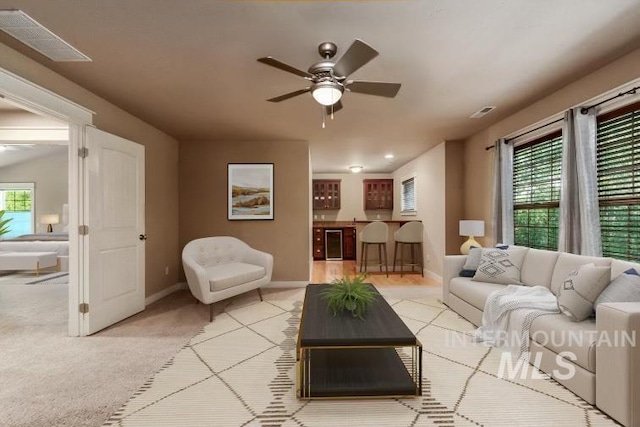 living room with wine cooler, ceiling fan, and light colored carpet