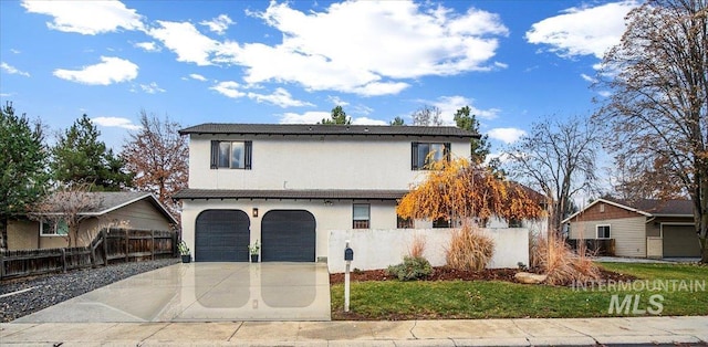 view of front of property with stucco siding, concrete driveway, a garage, and fence