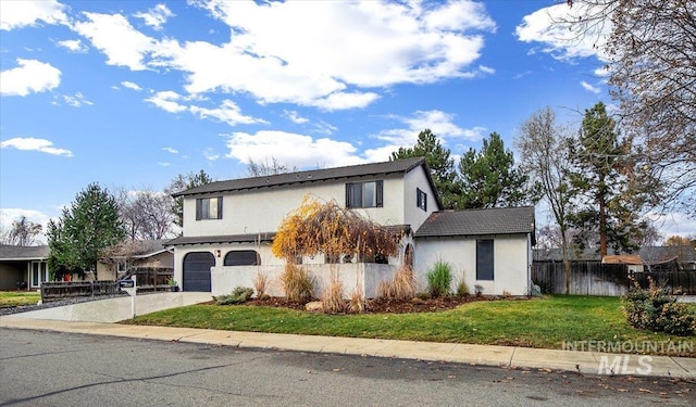 traditional-style house with stucco siding, fence, driveway, a garage, and a front yard