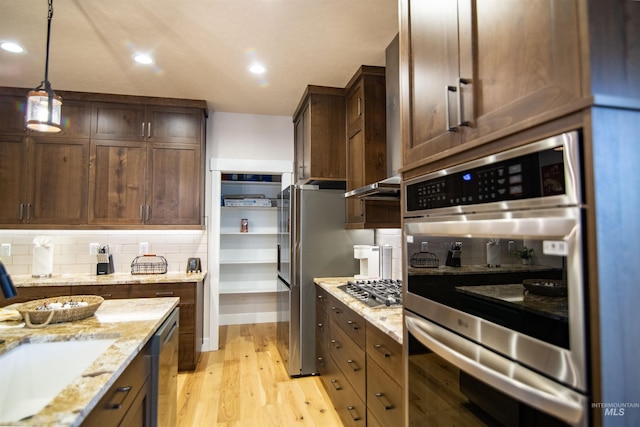 kitchen with tasteful backsplash, stainless steel appliances, light stone countertops, and sink