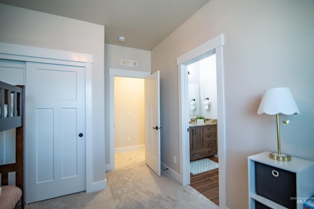 bedroom featuring light carpet, a closet, and ensuite bathroom