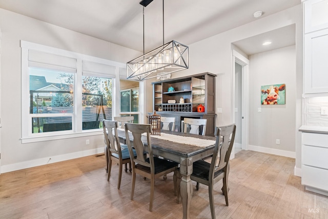 dining space with light hardwood / wood-style flooring and an inviting chandelier