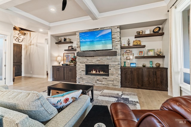 living room featuring beam ceiling, a stone fireplace, built in features, and light hardwood / wood-style flooring