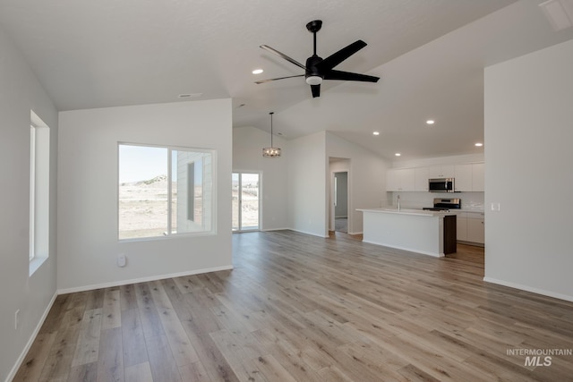 unfurnished living room with ceiling fan, sink, light hardwood / wood-style floors, and lofted ceiling