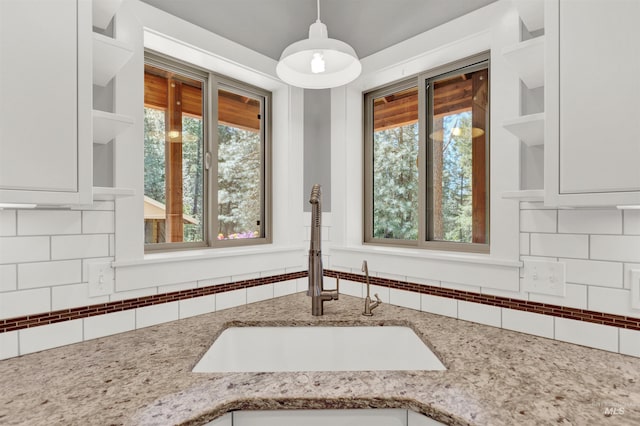 interior details with white cabinets, decorative backsplash, and sink