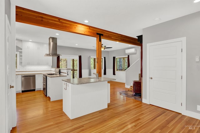 kitchen with appliances with stainless steel finishes, light wood-type flooring, island range hood, white cabinets, and a center island