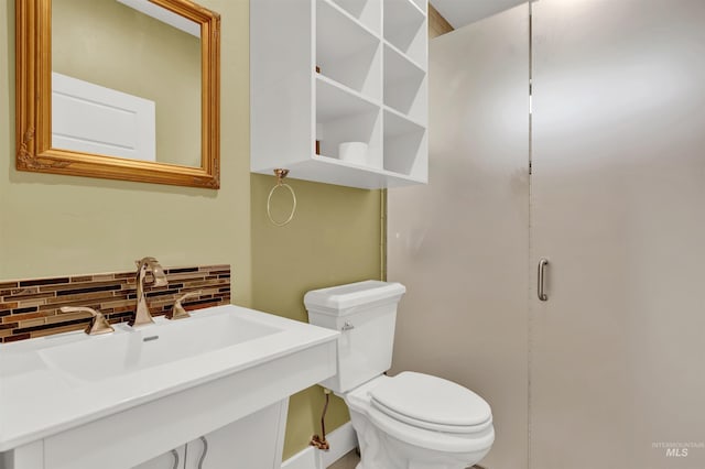 bathroom with toilet, sink, and backsplash