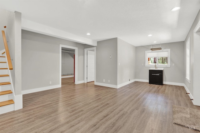 unfurnished living room with light hardwood / wood-style flooring and sink