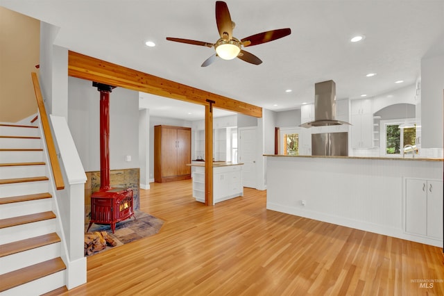 living room with a wood stove, ceiling fan, and light hardwood / wood-style flooring