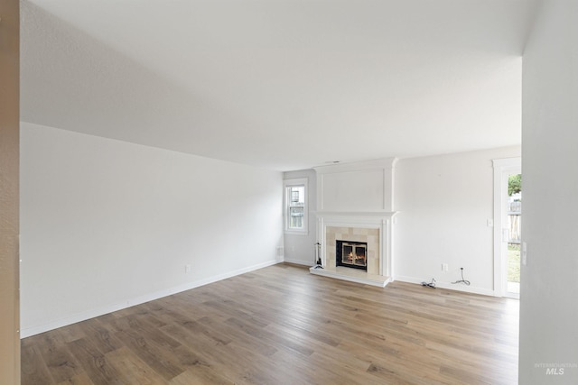 unfurnished living room featuring a tile fireplace and light hardwood / wood-style floors