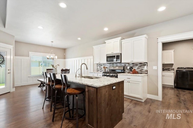 kitchen with white cabinetry, sink, stainless steel appliances, and an island with sink